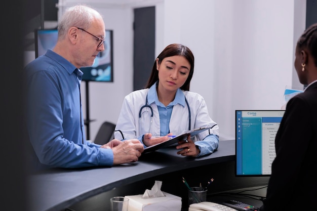 Lekarz przedstawiający raport z diagnozy choroby choremu starszemu pacjentowi omawiający leczenie opieki zdrowotnej w poczekalni szpitala. Medyk przepisuje leki, które pomagają radzić sobie z przewlekłym bólem mężczyzny.