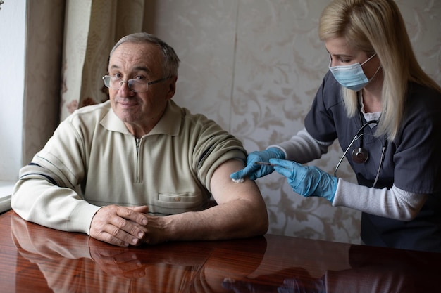 Lekarz przygotowujący szczepienie strzał do starszego pacjenta trzymając strzykawkę w domu - koncepcja kontroli zdrowia w domu dla seniorów podczas pandemii koronawirusa covid-19.