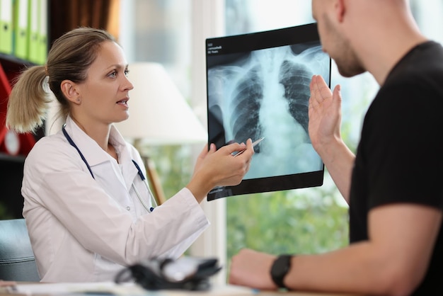 Lekarz rodzinny pokazuje pacjentowi zdjęcie rentgenowskie podczas wizyty w szpitalu, terapeuta wyjaśnia płuca