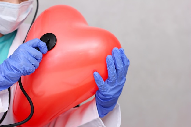 Zdjęcie lekarz słuchający stetoskopem dużego nadmuchiwanego serca pomysł na kardiologię i choroby serca