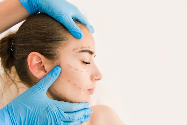 Lekarz sprawdzający skórę kobiety przed operacją plastyczną. Chirurg lub kosmetyczka ręce dotykając twarzy kobiety.