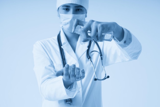 Lekarz stosujący spray antybakteryjny na rękę na białym tle