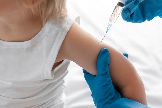 Lekarz szczepi chłopca w klinice Małe dziecko dostaje zastrzyk Pediatra szczepi dziecko w wieku 3 lat Szczepionka dla niemowlęcia Szczepienia dziecka Szczepienia dzieci Pojęcie zdrowia