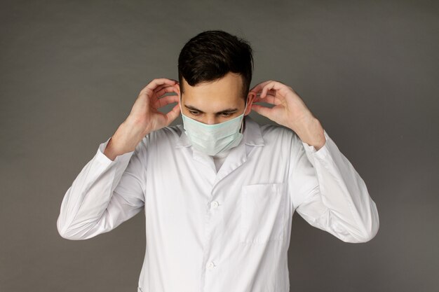 Lekarz trzyma i zakłada maskę medyczną, aby chronić przed koronawirusem