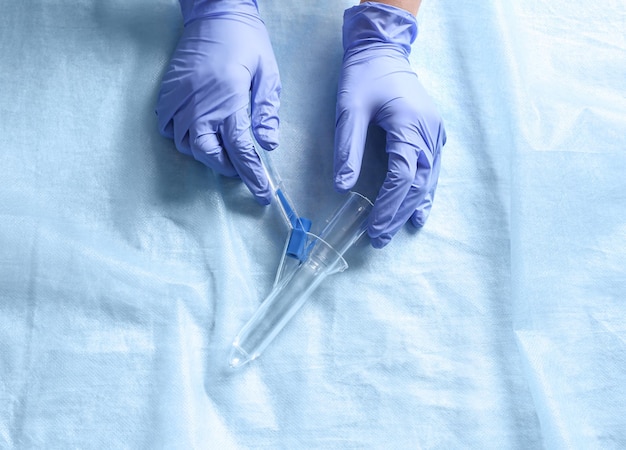 Zdjęcie lekarz trzymający anoskop na jasnoniebieskiej tkaninie widok z góry leczenie hemoroidów