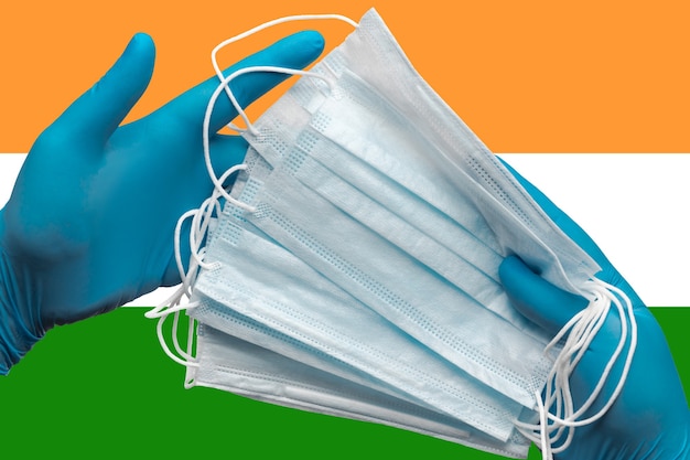 lekarz trzymający maski na twarz w rękach niebieskie rękawiczki medyczne na tle flaga narodowa indii koncepcja
