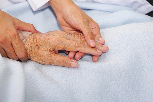 Lekarz trzymający rękę pacjentki starszej lub starszej starszej kobiety i zachęcający w szpitalu