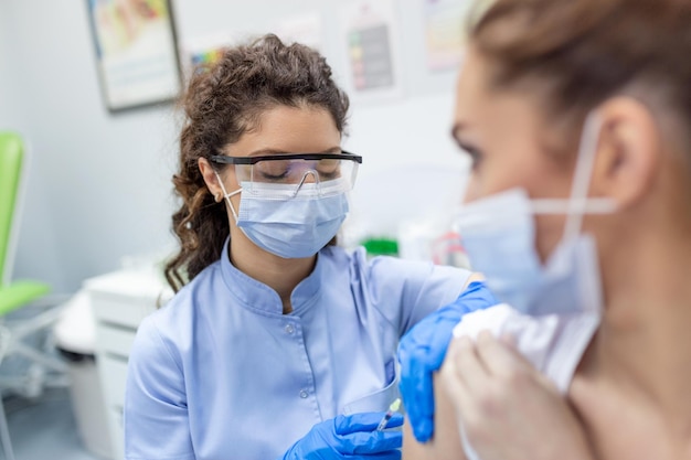 Lekarz Trzymający Strzykawkę Dokonującą Covid 19 Dawka Wstrzyknięcia Szczepienia W Ramię Pacjentki Noszącej Maskę Szczepionka Przeciw Grypie Badania Kliniczne Koncepcja Koronawirusa Leczenie Zbliżenie Widok