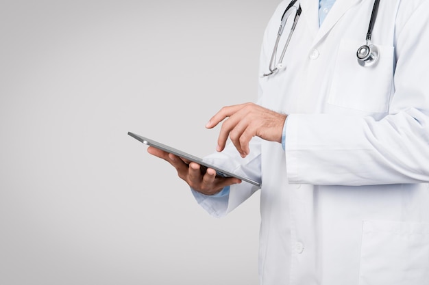 Lekarz używający tabletu cyfrowego biały płaszcz szare tło wolna przestrzeń