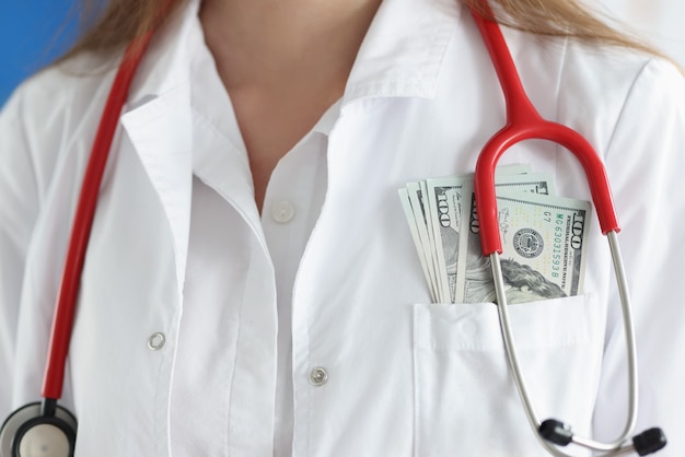 Zdjęcie lekarz w białym fartuchu ma gotówkę w kieszeni na piersi