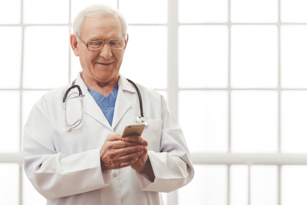 Lekarz w białym fartuchu medycznym używa smartfona.