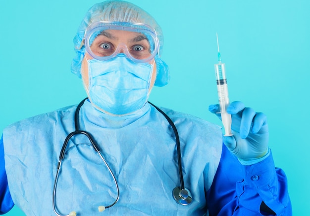 Lekarz w kombinezonie ochronnym ze strzykawką w ręku. Lekarz w masce medycznej przygotowuje zastrzyk ze szczepionką.