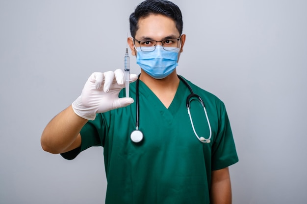 Lekarz w masce medycznej i rękawiczkach trzyma strzykawkę z koronawirusem szczepionkowym leczy pacjentów w szpitalu na białym tle