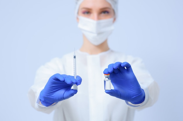 Lekarz w rękawiczkach medycznych i masce trzyma w rękach szczepionkę
