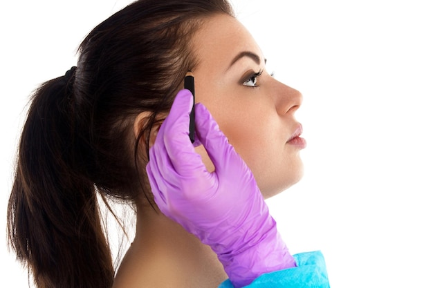 Lekarz w rękawiczkach wstrzykuje botox z igłą w skroń pacjenta przeciwko