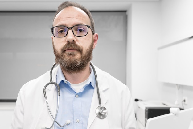 Lekarz w średnim wieku ubrany w biały fartuch medyczny w klinice z poważnym wyrazem twarzy