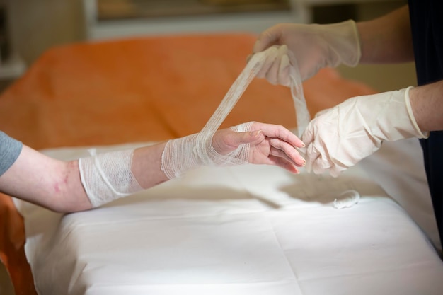 Zdjęcie lekarz wiąże rękę pacjenta bandażem medycznym