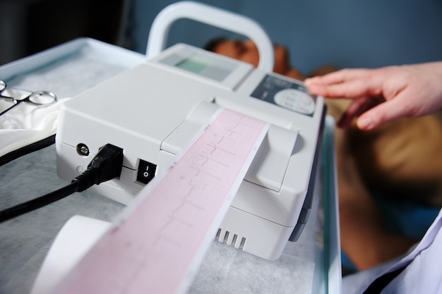 Lekarz z elektrokardiogramem sprzęt do badania kardiogramu męskiego pacjenta w klinice szpitalnej