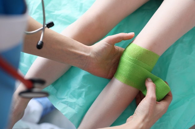 Zdjęcie lekarz zakłada bandaż na zranioną nogę dziecka