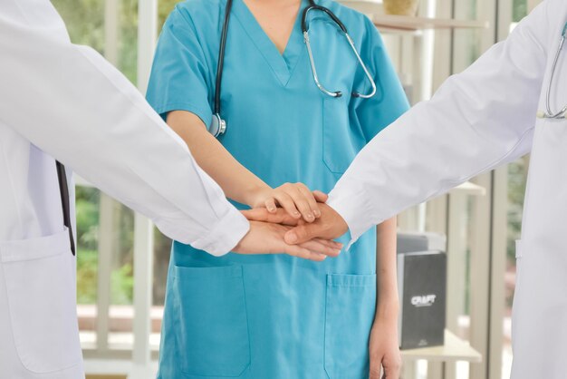 Zdjęcie lekarze i pielęgniarki w zespole medycznym stawiają ręce koncepcja pracy zespołowej w szpitalu dla sukcesu praca i zaufanie do zespołu