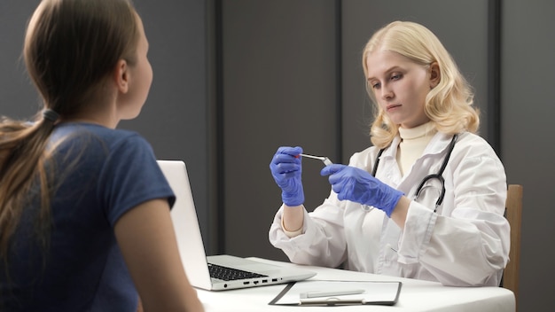 Lekarze podają niebieskie ochronne rękawiczki medyczne, pobierając wymaz z nosa w celu zasiedlenia dorosłym w mobilnym laboratorium