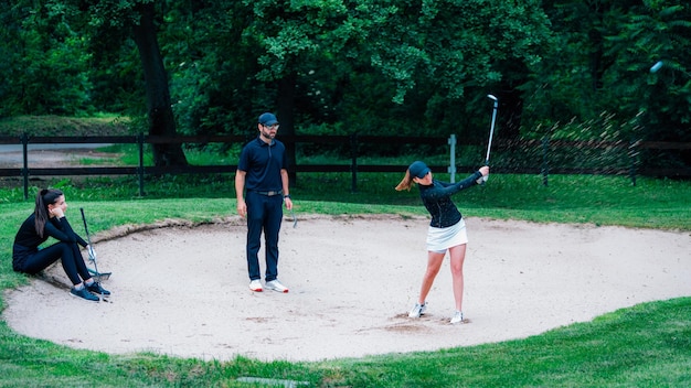 Lekcje golfa Młoda kobieta ma lekcję gry w golfa z bunkra piasku