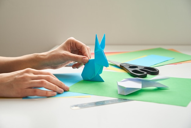 Lekcje origami. Kobieta robi królika wielkanocnego origami z kolorowego papieru