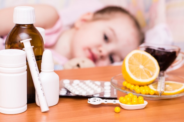 Leki i witaminy na stole dziecko w łóżku z ospą wietrzną