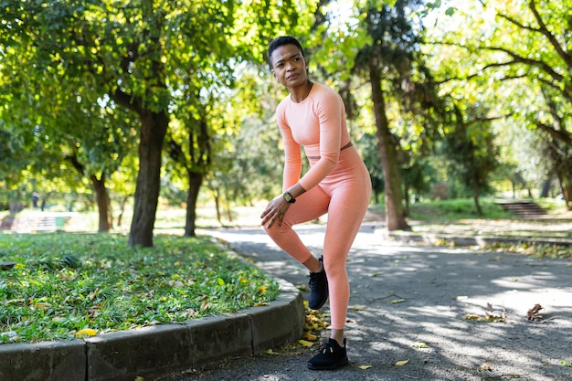 Lekkoatletka ma silny ból nóg po porannym joggingu i fitnessie, Afroamerykanka rano w jesiennym parku