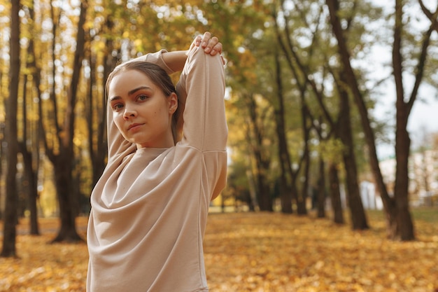 lekkoatletka rozciągająca podniesione ręce za plecami podczas ćwiczeń podczas fitnessu na świeżym powietrzu