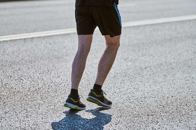 Lekkoatletycznego mężczyzna joggingu w odzieży sportowej na drodze miasta