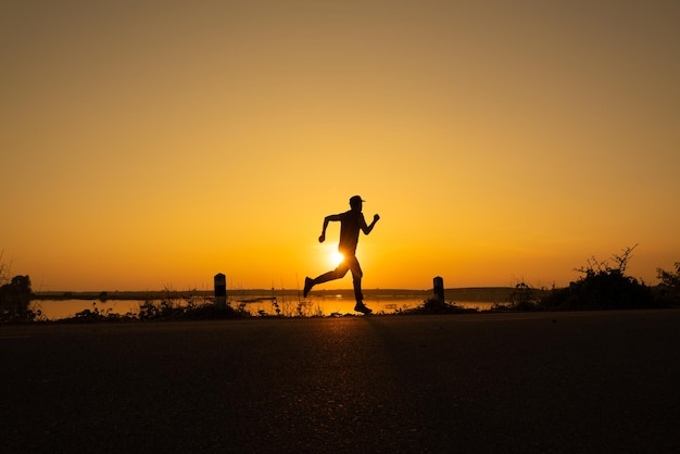 Lekkoatletyczny biegacz rozpoczyna trening na monitorze fitness lub inteligentnym zegarku i czeka w pobliżu zachodu słońca Bieganie w terenie i koncepcja aktywnego stylu życia sylwetka zdjęcie