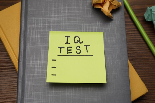 Zdjęcie lepki papier ze słowami test iq zeszyty i ołówek na drewnianym stole powyżej widoku