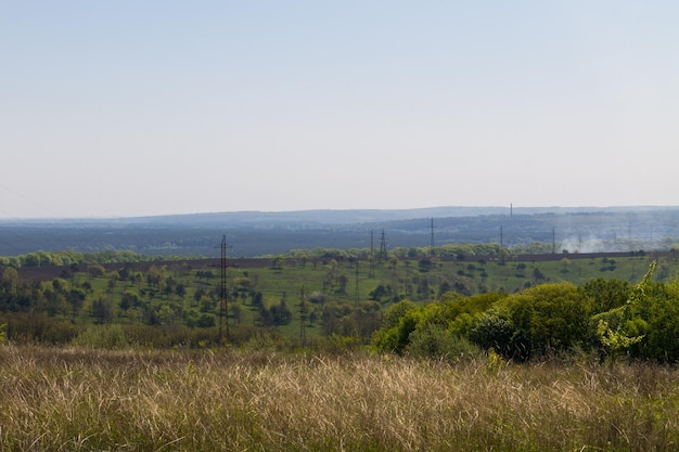 Letni krajobraz z zielonymi wzgórzami i drzewami linii energetycznej