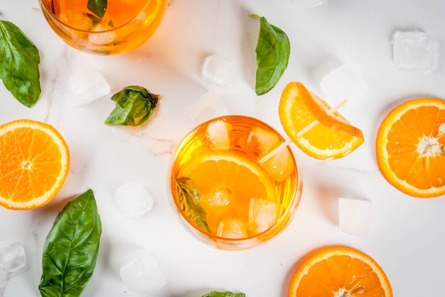 Letni orzeźwiający napój, lemoniada, koktajl z pomarańczą i bazylią. Na białym marmurowym stole skopiuj widok z góry miejsca