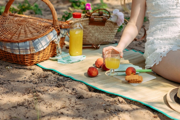 Letni piknik na plaży nad morzem Ciasteczka z sokiem ze świeżych owoców i brzoskwinie w pobliżu kosza piknikowego na szmatce