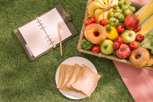 Letni piknik na trawie z otwartym koszem piknikowym, owocami, sałatką i ciastem wiśniowym