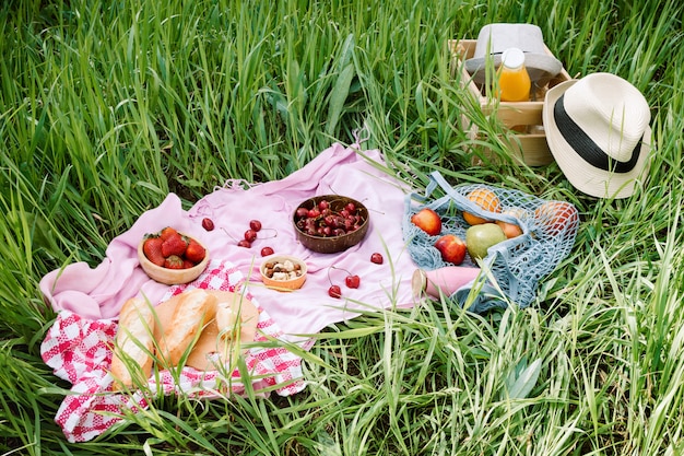 letni piknik na trawie z wiśniami, świeżym chlebem i szklaną butelką soku