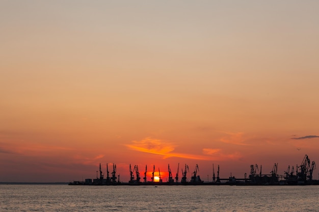 Letni pomarańczowy zachód słońca nad Morzem Azowskim na tle portu w Berdiańsku