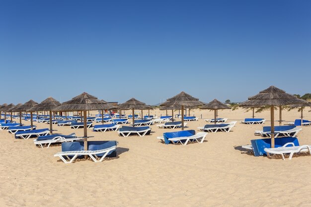 Letni poranek na plaży Algarve. Leżaki na piasku.