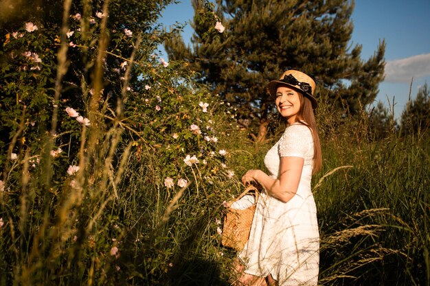Letni portret młodej kobiety w pobliżu krzewu dzikiej róży