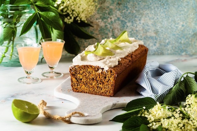 Letni słodki bochenek na stole z kwiatami i napojem w okularach. z kremem kokosowym i limonką. deser na brunch lub poranne śniadanie