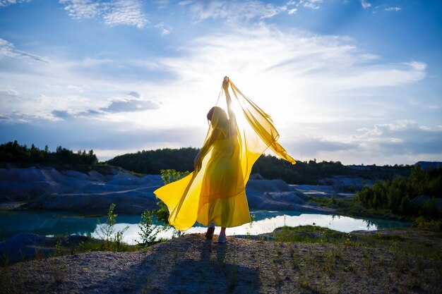 Zdjęcie letni styl życia oszałamiająca szczęśliwa kobieta biegająca w przyrodzie. w długiej żółtej sukience. romantyczny nastrój. ciesząc się słońcem. słoneczny dzień. selektywne skupienie