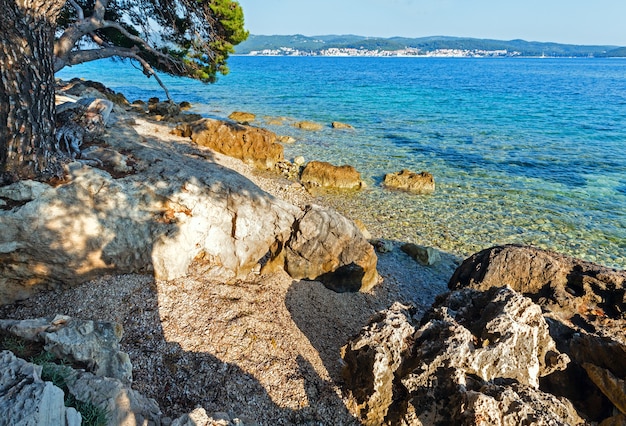 Letnia kamienista plaża i czysta powierzchnia wody Adriatyku (Chorwacja)