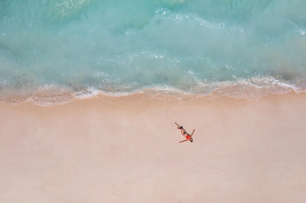 Letnia koncepcja beztroskiej wolności lotniczej. Opalanie dziewczyna w bikini na plaży na białym piasku strzał