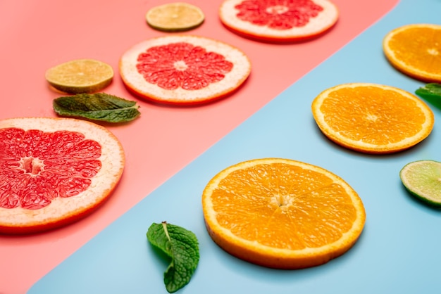 Letnia koncepcja tła w plasterkach pomarańczy, grejpfruta, cytryny, limonki na różowym i niebieskim tle