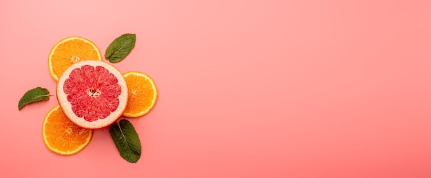 Zdjęcie letnia koncepcja tła w plasterkach pomarańczy, grejpfruta, mięty na różowym tle
