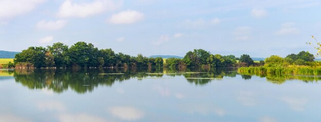 Letnia panorama krajobrazu z rzeką i drzewami odbitymi w wodzie rzeki