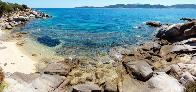 Letnia sceneria morza z akwamarynową przezroczystą wodą i piaszczystą plażą. Widok z brzegu (Sithonia, Halkidiki, Grecja).