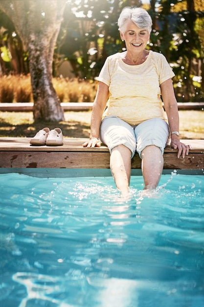 Letnia starsza kobieta i stopy w basenie relaksują się, a podczas weekendowej przerwy szczęście i spokój Odprężające dojrzałe nogi kobiet i kobiet na wakacjach i wakacjach z emeryturą i słońcem